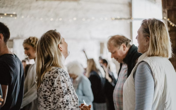 Small group of people gathered indoors listening to someone speak